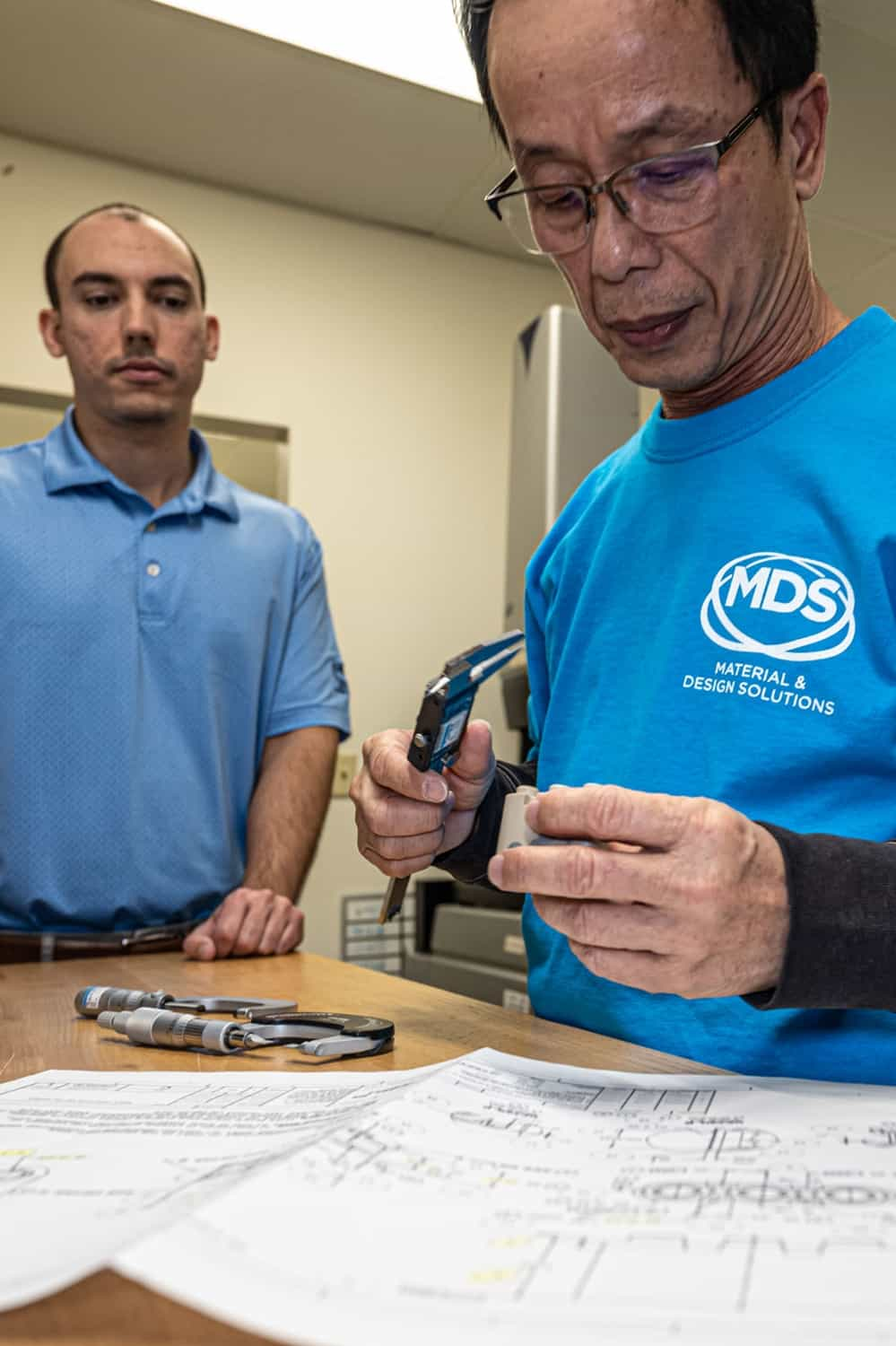 Two team members closely inspecting a plastic part.