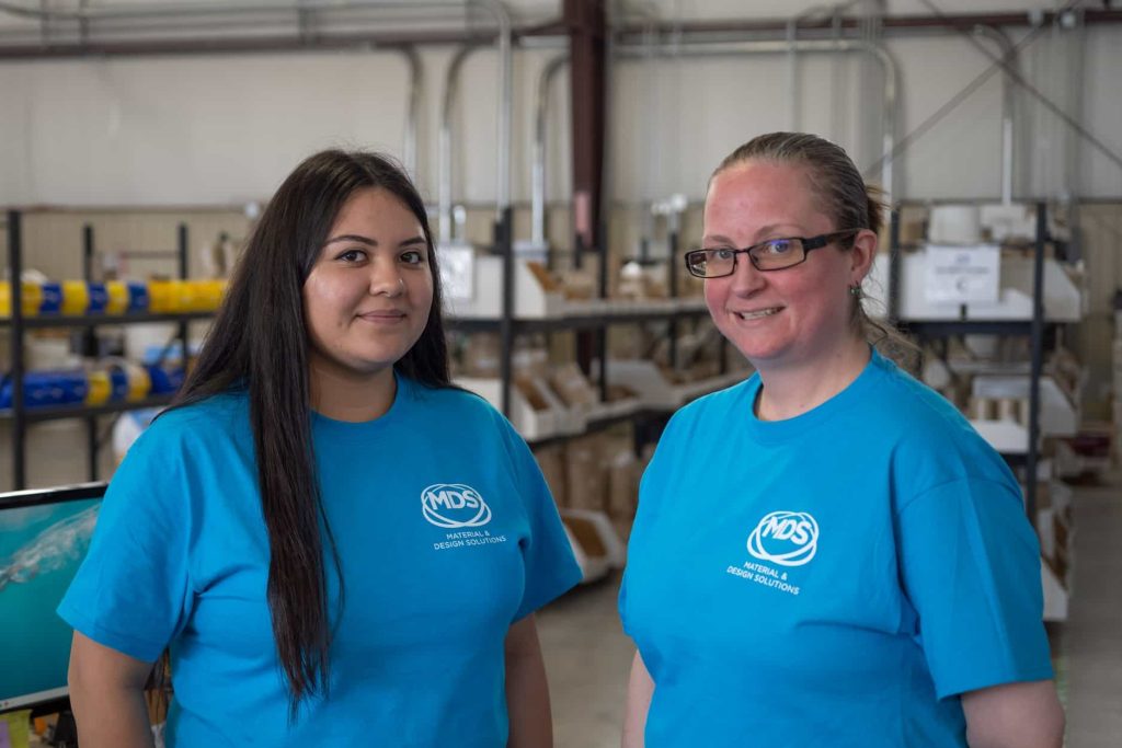 Two female team members smile for the camera.